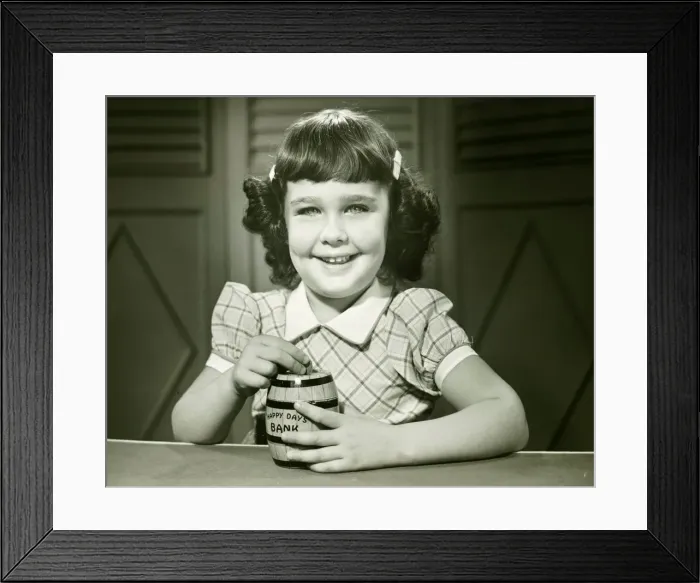 Framed Print : Girl (6-7) putting coin into money-box, (B&W), (Close-up), (Portrait) Framed Print : Girl (6-7) putting coin into money-box, (B&W), (Close-up), (Portrait)