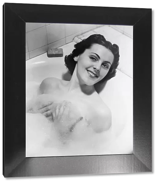 Woman taking bath in bathtub (B&W), portrait