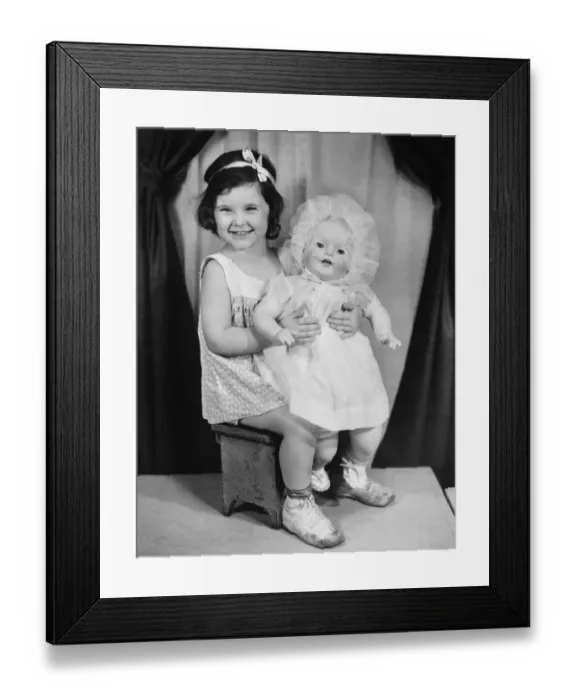 Framed Print : Girl (4-5) holding doll, posing in studio (B&W), portrait