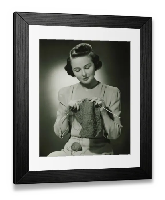 Framed Print : Young woman knitting in studio, (B&W) Framed Print : Young woman knitting in studio, (B&W)