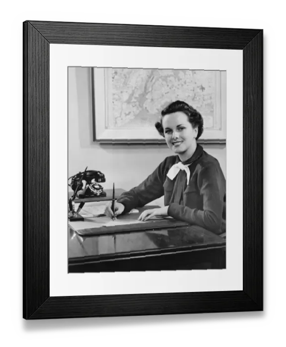 Framed Print : Young woman sitting at desk, writing, (B&W) Framed Print : Young woman sitting at desk, writing, (B&W)