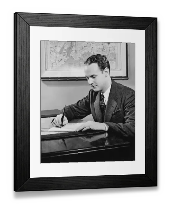 Framed Print : Young businessman sitting at desk, writing, (B&W) Framed Print : Young businessman sitting at desk, writing, (B&W)