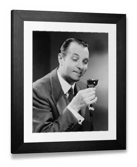 Framed Print : Businessman with glass of beverage, posing in studio, (B&W), close-up Framed Print : Businessman with glass of beverage, posing in studio, (B&W), close-up