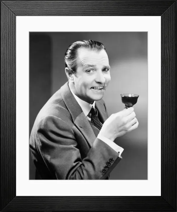 Framed Print : Businessman with glass of beverage, posing in studio, (B&W), portrait Framed Print : Businessman with glass of beverage, posing in studio, (B&W), portrait