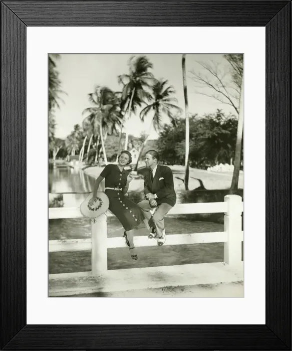 Framed Print : Elegant couple sitting on fence in tropical environment, (B&W) Framed Print : Elegant couple sitting on fence in tropical environment, (B&W)