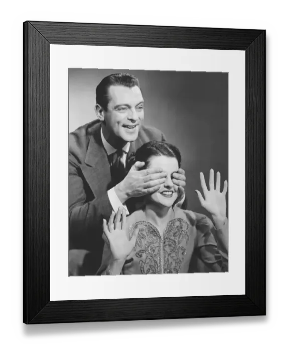 Framed Print : Man standing behind woman, covering her eyes (B&W)