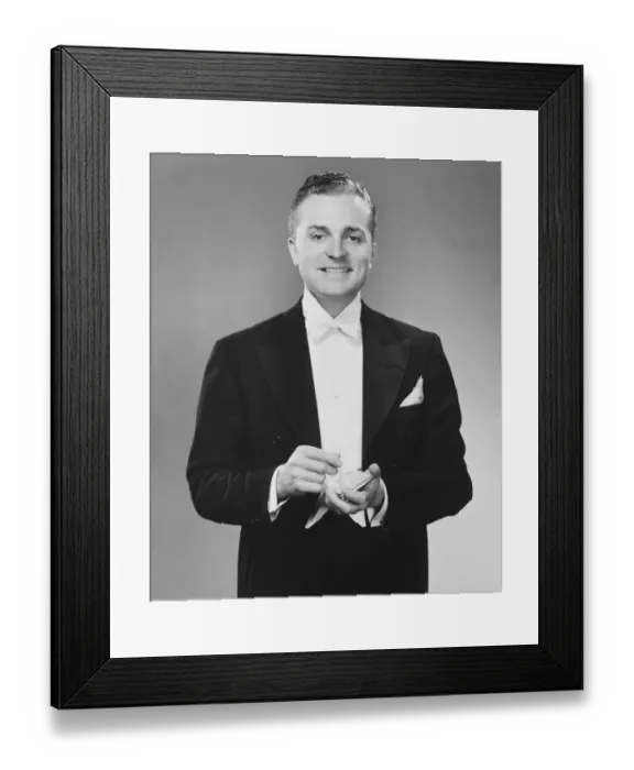 Framed Print : Man in dinner jacket holding cigarette and cigarette case standing in studio, (B&W), portrait Framed Print : Man in dinner jacket holding cigarette and cigarette case standing in studio, (B&W), portrait