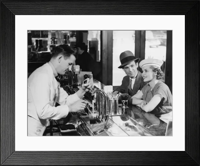 Framed Print : Bartender pouring beer for young couple in bar, (B&W) Framed Print : Bartender pouring beer for young couple in bar, (B&W)