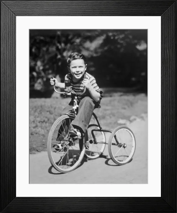 Framed Print : Young boy (6-7) riding tricycle in park, (B&W), portrait Framed Print : Young boy (6-7) riding tricycle in park, (B&W), portrait