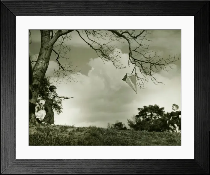 Framed Print : Boy (6-7) flying kite in park, (B&W) Framed Print : Boy (6-7) flying kite in park, (B&W)