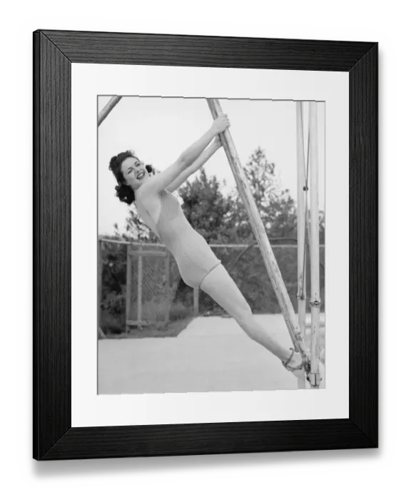 Framed Print : Woman in swimsuit hanging from wooden construction (B&W), portrait Framed Print : Woman in swimsuit hanging from wooden construction (B&W), portrait