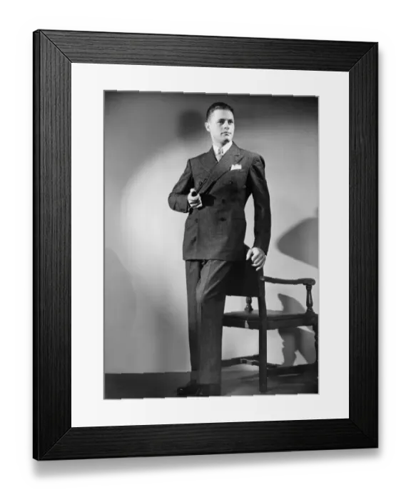 Framed Print : Man with pipe posing by chair in studio, (B&W), portrait