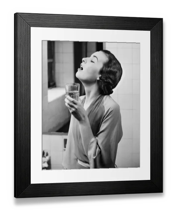 Framed Print : Young woman in bathroom gargling water, (B&W)