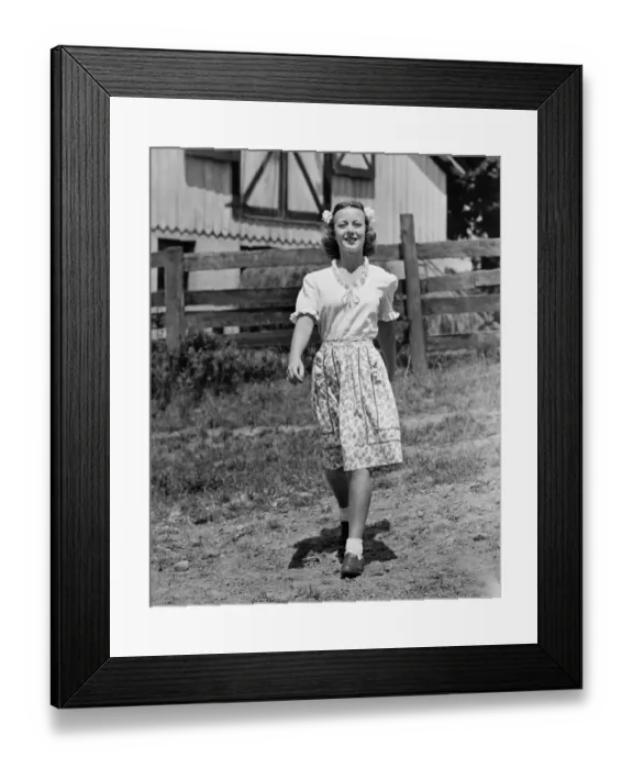 Framed Print : Young woman walking on dirt road by farmhouse, (B&W) Framed Print : Young woman walking on dirt road by farmhouse, (B&W)