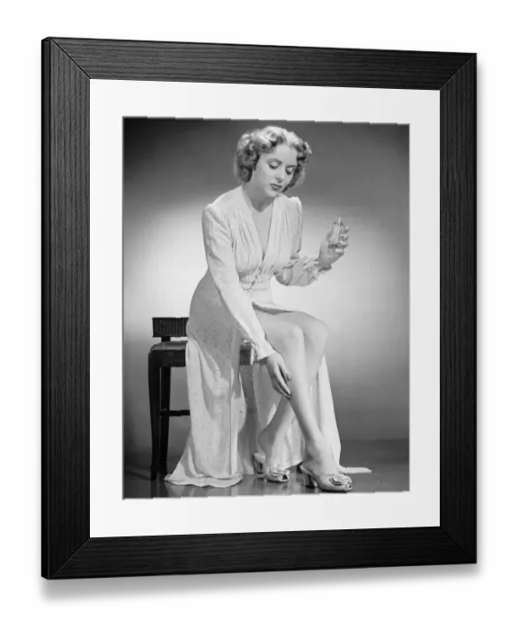 Framed Print : Woman applying perfume on leg, (B&W), portrait