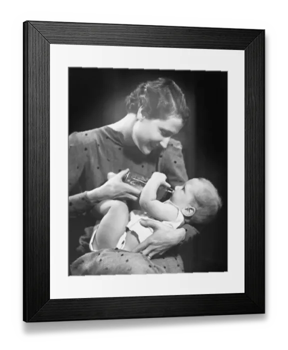 Framed Print : Woman feeding baby (6-9 months) in studio (B&W) Framed Print : Woman feeding baby (6-9 months) in studio (B&W)