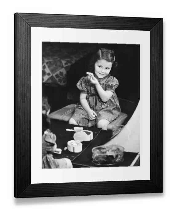Framed Print : Reflection of girl (4-5) sitting in front of mirror, applying face powder (B&W), elevated view