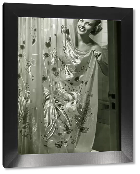 Woman leaning from behind shower curtain, (B&W)