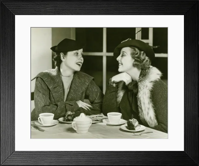 Framed Print : Two young women chatting, having coffee and cake, (B&W) Framed Print : Two young women chatting, having coffee and cake, (B&W)