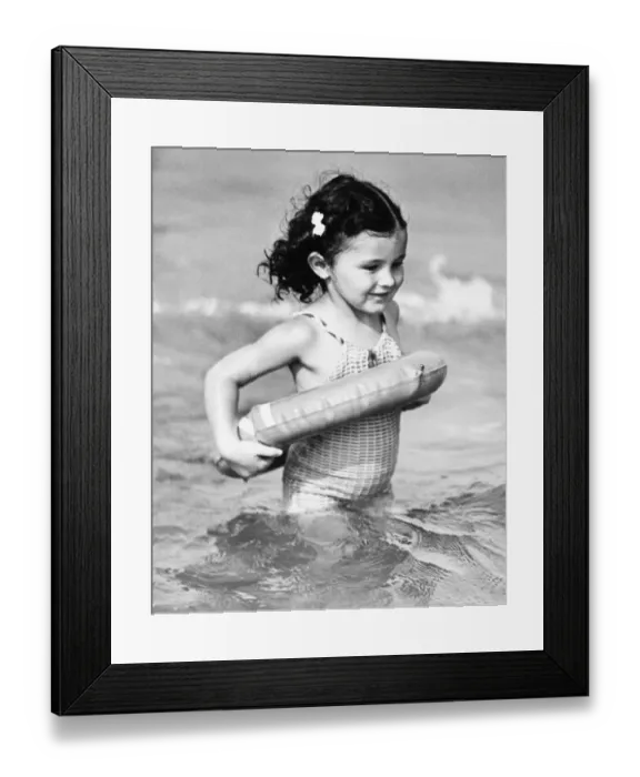 Framed Print : Girl (4-5) standing in water with inflatable ring (B&W) Framed Print : Girl (4-5) standing in water with inflatable ring (B&W)