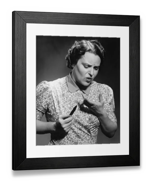 Framed Print : Mature woman looking at cut on finger in studio (B&W)