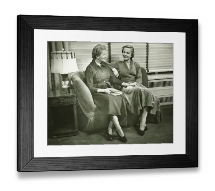 Framed Print : Two women sitting on sofa, talking, indoors, (B&W) Framed Print : Two women sitting on sofa, talking, indoors, (B&W)
