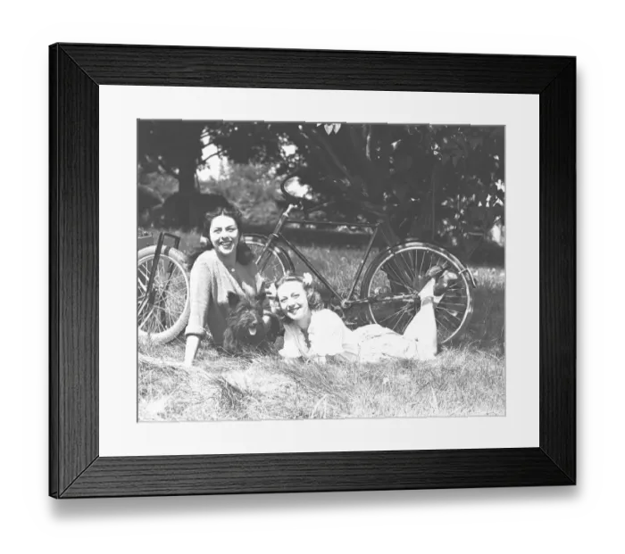 Framed Print : Two women and dog resting on grass, (B&W) Framed Print : Two women and dog resting on grass, (B&W)