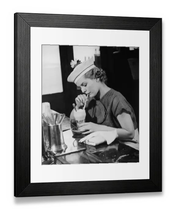 Framed Print : Young woman in fancy hat drinking ice cream soda (B&W) Framed Print : Young woman in fancy hat drinking ice cream soda (B&W)