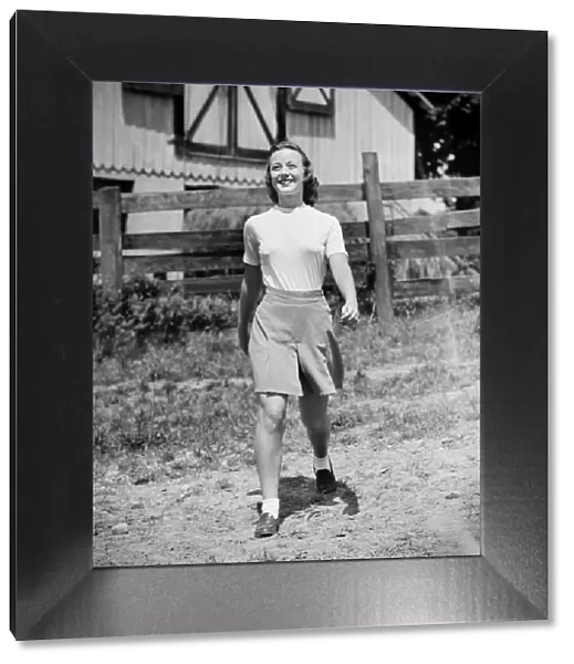Young woman walking in front of cottage house (B&W)