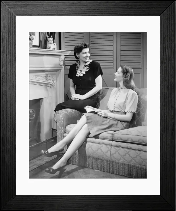 Framed Print : Two women sitting on couch, discussing, (B&W) Framed Print : Two women sitting on couch, discussing, (B&W)