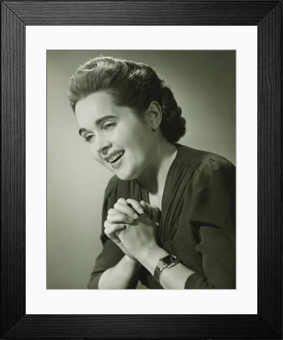 Framed Print : Young woman with hands put together smiling in studio (B&W), close-up Framed Print : Young woman with hands put together smiling in studio (B&W), close-up