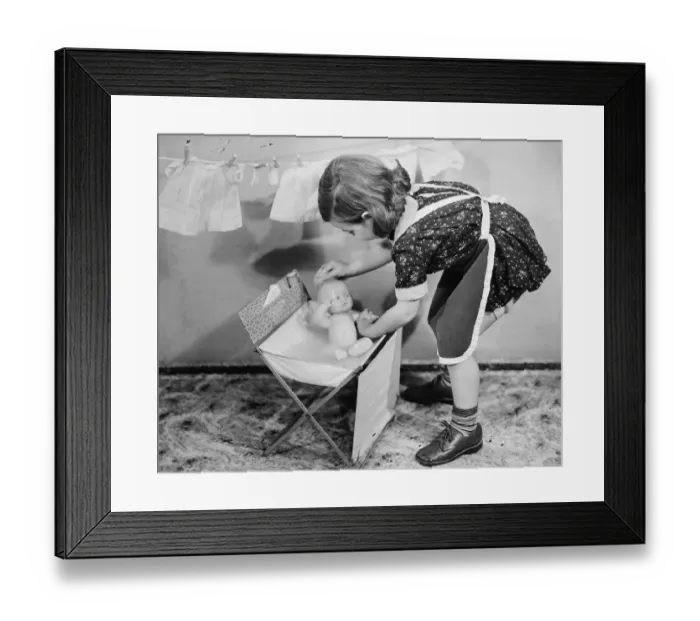 Framed Print : Girl (8-9) playing with doll, (B&W) Framed Print : Girl (8-9) playing with doll, (B&W)