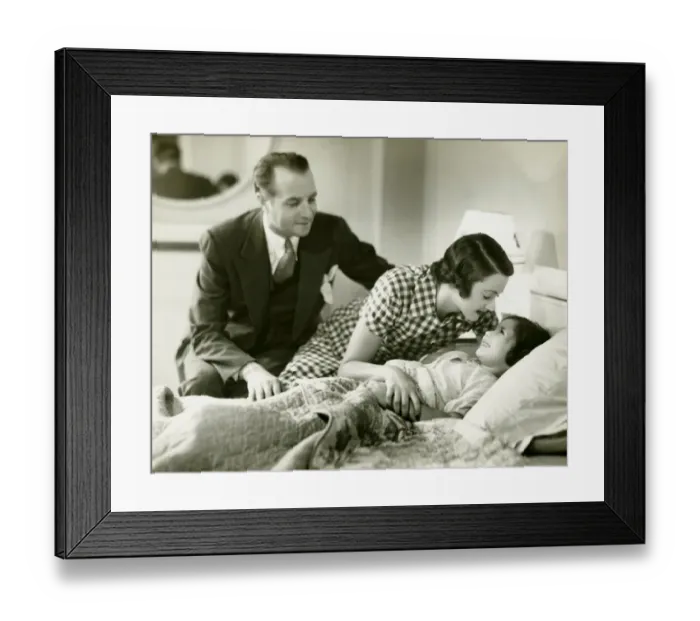 Framed Print : Parents tucking daughter (6-7) into bed, (B&W)