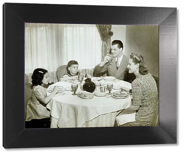 Family sitting around table, having meal, children (4-5) (6-7), (B&W)