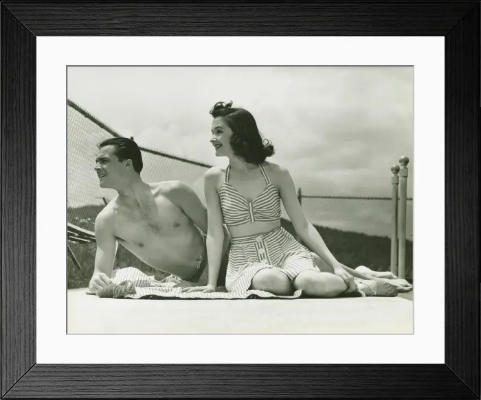 Framed Print : Young couple in beachwear relaxing outdoors, (B&W) Framed Print : Young couple in beachwear relaxing outdoors, (B&W)