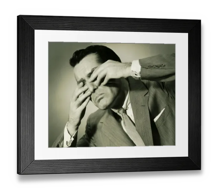 Framed Print : Businessman in studio covering eyes with fingers, (B&W), close-up Framed Print : Businessman in studio covering eyes with fingers, (B&W), close-up