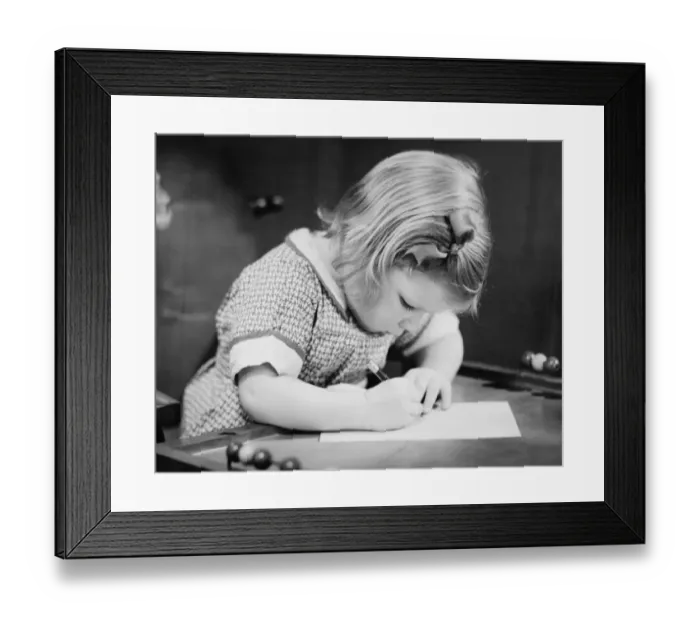 Framed Print : Young girl (4-5) working on school table, (B&W), close-up Framed Print : Young girl (4-5) working on school table, (B&W), close-up