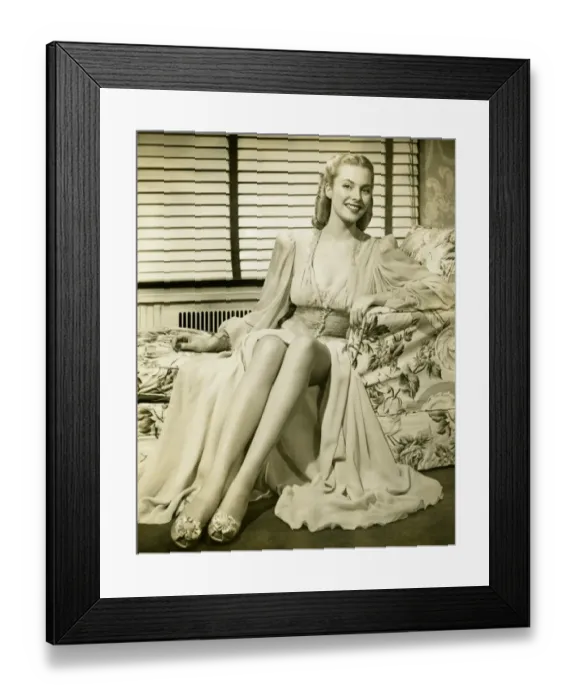 Framed Print : Glamorous woman sitting on couch, showing legs, (B&W), portrait Framed Print : Glamorous woman sitting on couch, showing legs, (B&W), portrait