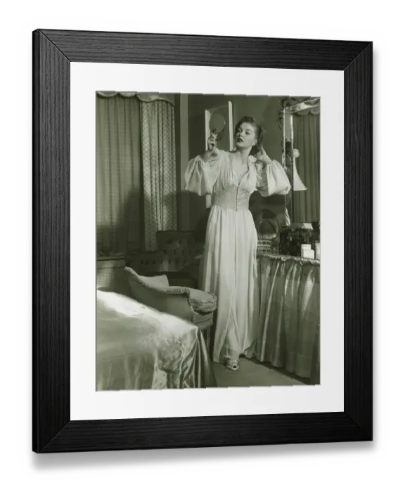 Framed Print : Woman in fashionable gown looking at mirror in bedroom, (B&W) Framed Print : Woman in fashionable gown looking at mirror in bedroom, (B&W)