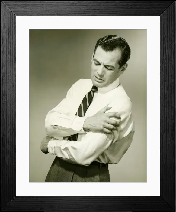 Framed Print : Businessman with aching arm in studio, (B&W) Framed Print : Businessman with aching arm in studio, (B&W)