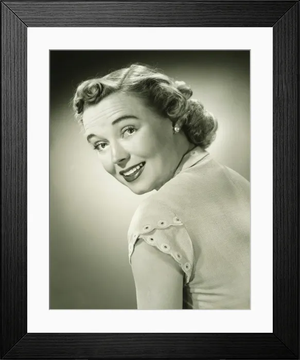 Framed Print : Smiling woman looking over shoulder in studio, (B&W), portrait Framed Print : Smiling woman looking over shoulder in studio, (B&W), portrait