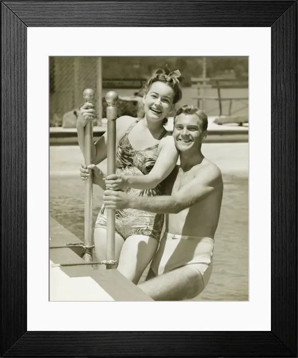 Framed Print : Couple standing at railings in pool, (B&W), portrait