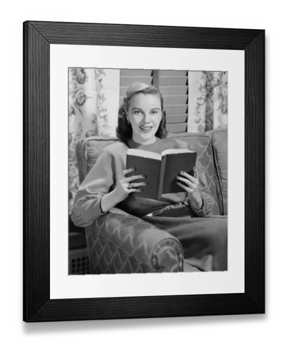 Framed Print : Woman reading book in living room, (B&W), portrait Framed Print : Woman reading book in living room, (B&W), portrait