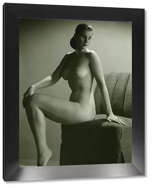 Naked woman sitting on chair in studio, (B&W), portrait