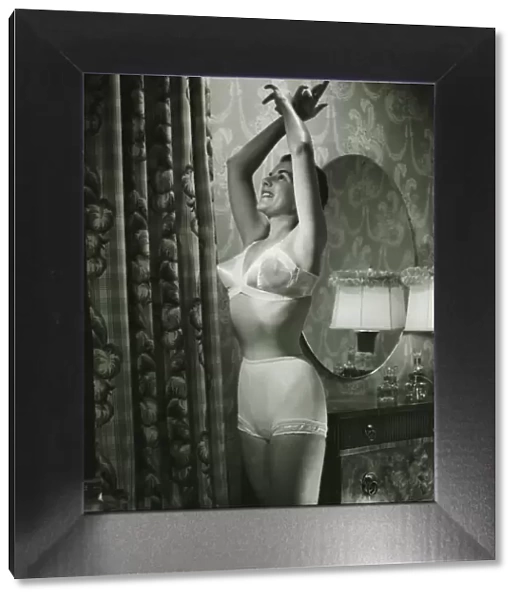 Woman in underwear stretching in bedroom, (B&W)