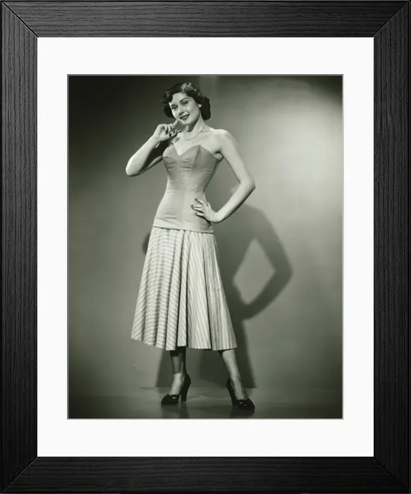 Framed Print : Young woman standing in studio, smiling, (B&W) Framed Print : Young woman standing in studio, smiling, (B&W)