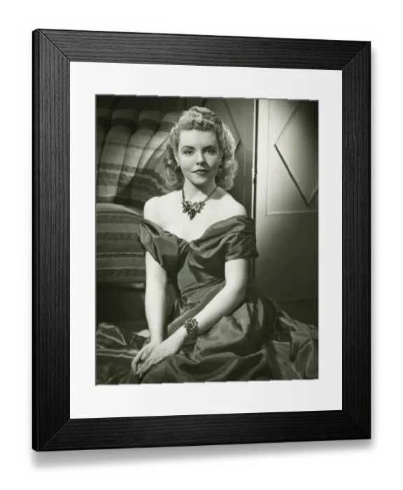 Framed Print : Young woman in evening dress sitting indoors, (B&W), portrait Framed Print : Young woman in evening dress sitting indoors, (B&W), portrait