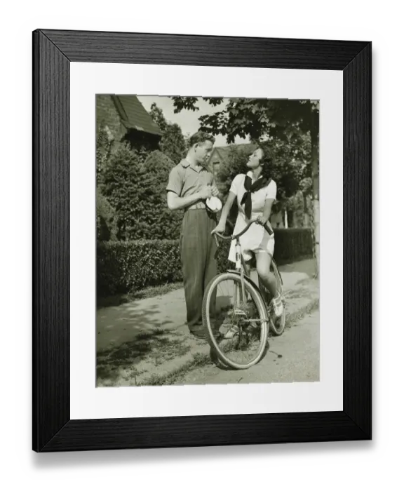 Framed Print : Young couple talking on street, woman on bicycle, (B&W)