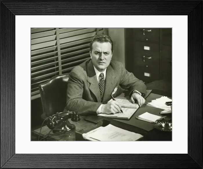 Framed Print : Businessman writing in notepad, sitting at office, (B&W) Framed Print : Businessman writing in notepad, sitting at office, (B&W)