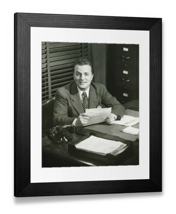 Framed Print : Businessman holding documents, sitting at office, (B&W) Framed Print : Businessman holding documents, sitting at office, (B&W)